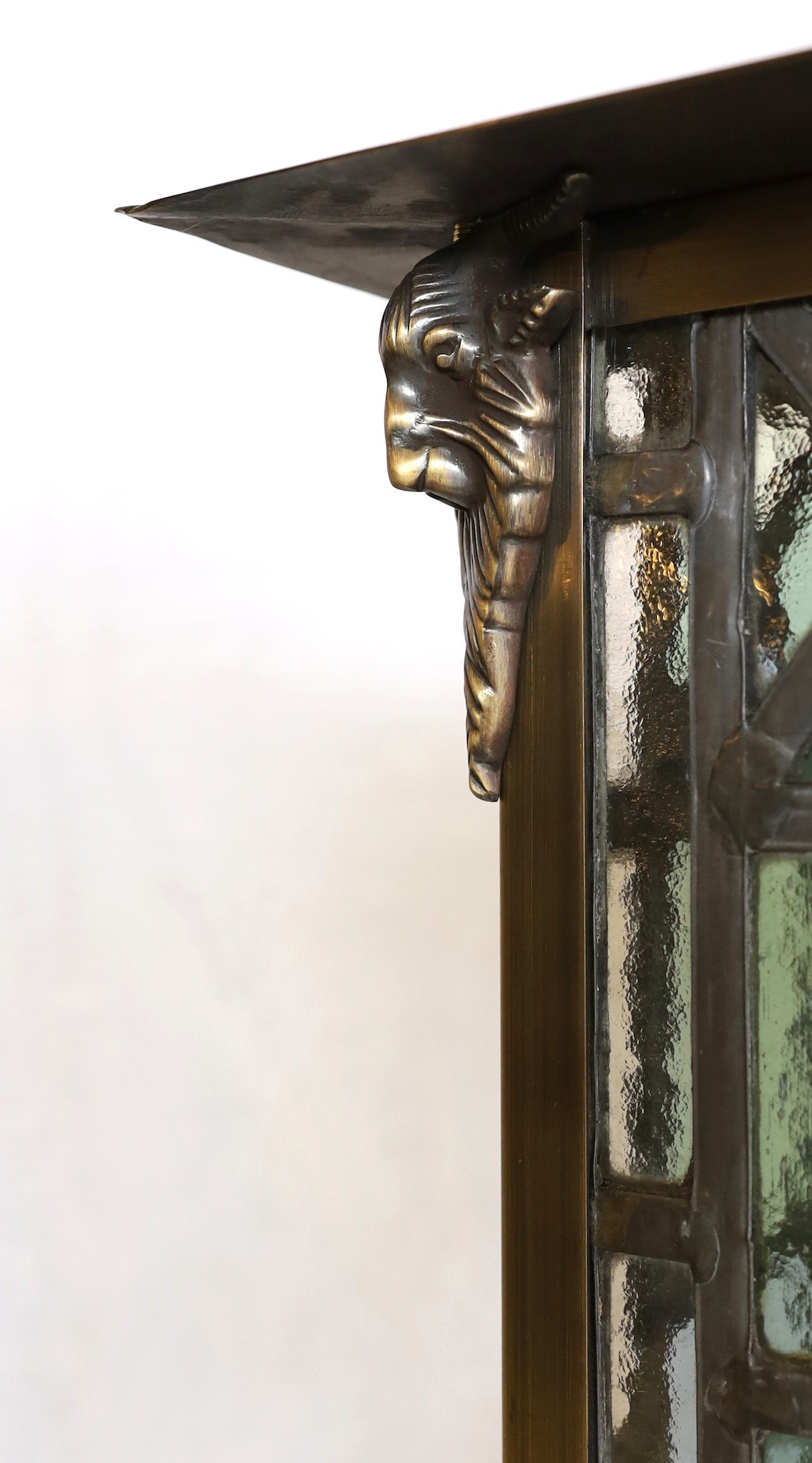 A large Edwardian lacquered brass and leaded glass hall lantern applied with rams head motifs, height 70cm. width 46cm